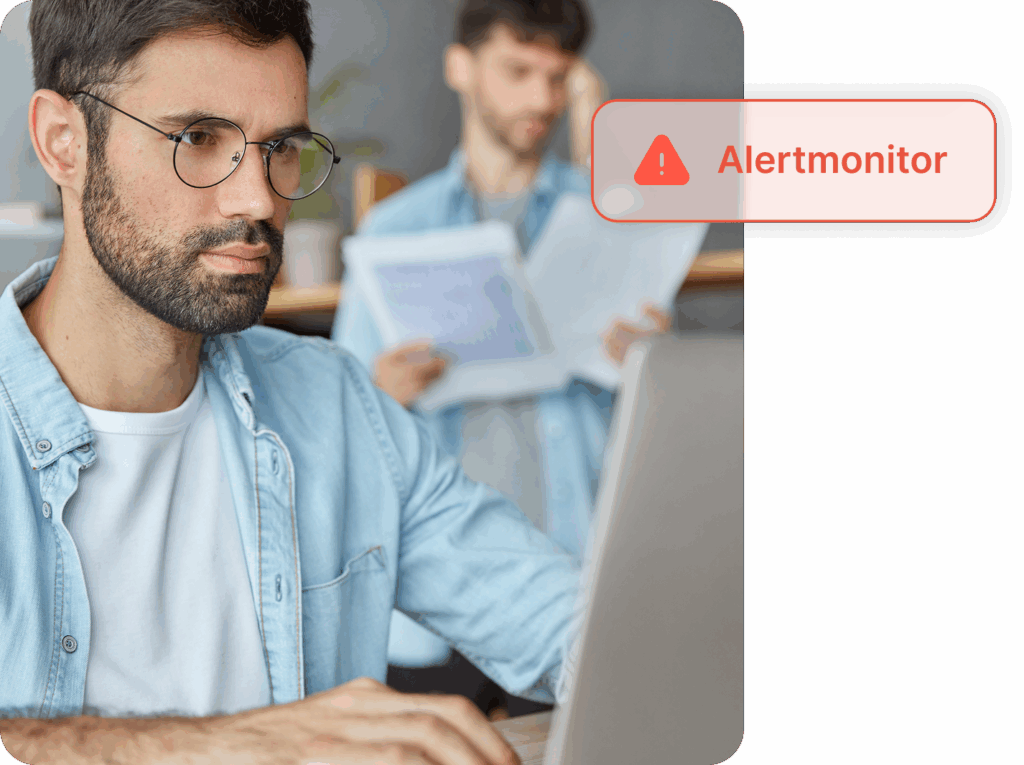 Mann mit Brille sitz am Laptop. Davor ist eine Grafik mit dem Warnhinweis "Alertmonitor".